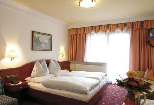 ein Hotelzimmer mit einem Bett und einem Fenster in der Unterkunft Der Alpenhof Maria Alm in Maria Alm am Steinernen Meer