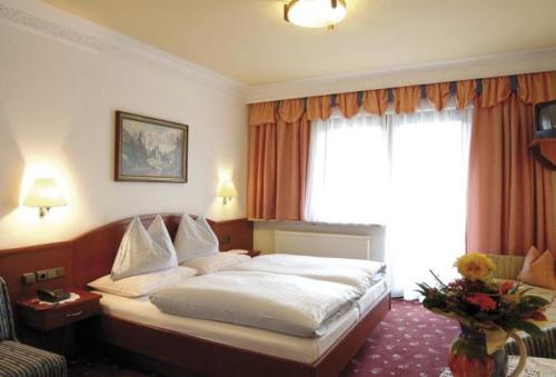 a hotel room with a bed and a window at Der Alpenhof Maria Alm in Maria Alm am Steinernen Meer