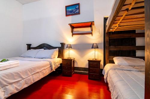 two beds in a room with two lamps on tables at Hotel Casa del Colibri in Güicán