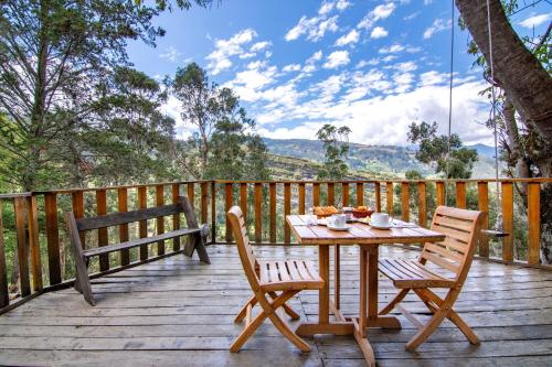 a wooden deck with a table and two chairs at Hotel Casa del Colibri in Güicán