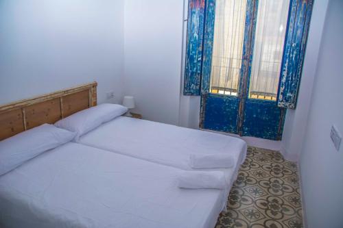 a small bedroom with a bed and two windows at Pigal in Tarragona