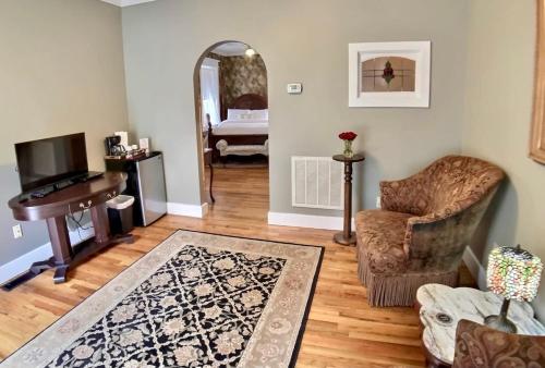 a living room with a piano and a chair and a mirror at Brownstone Spring Suite - Double Spa Tub Parking in Eureka Springs