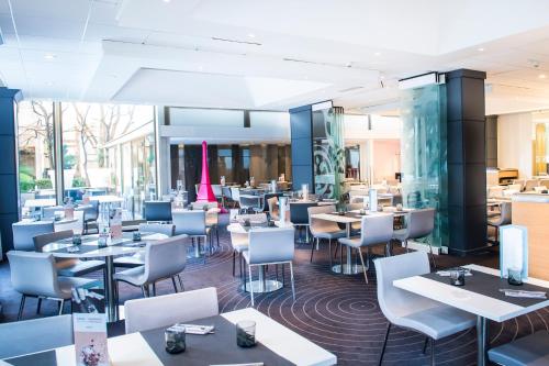 a restaurant with white tables and chairs and tablesktop at Mercure Paris Centre Tour Eiffel in Paris