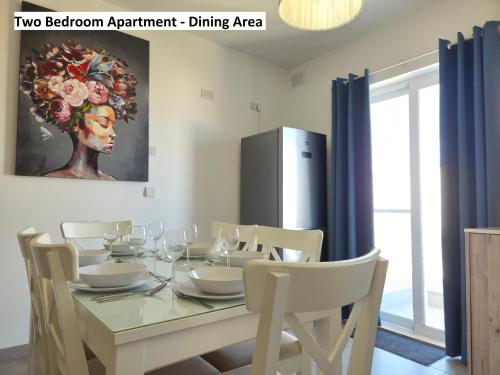 a dining room with a table with chairs and a painting at Blue Sky Apartments in Mġarr