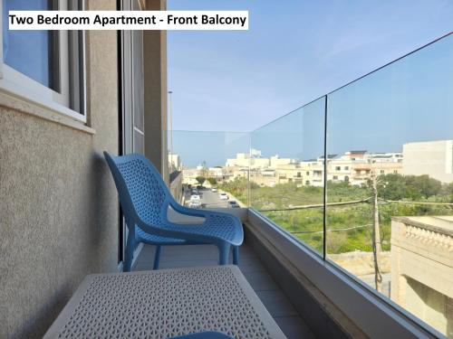 two chairs on a balcony with a view of a city at Blue Sky Apartments in Mġarr