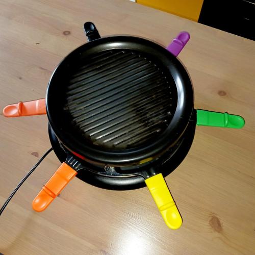 a pan sitting on top of a table with colorful tongs at La Source - appart 85 m2 & terrasse privée rdc in Orcival