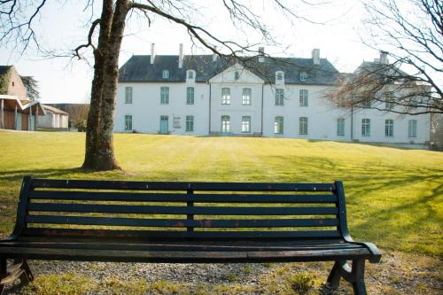 a park bench in front of a large white house at Surprenantes - Château du Pé in Saint-Jean-de-Boiseau