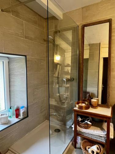 une douche avec une porte vitrée dans une salle de bain dans l'établissement Cottage du Long Vey, à La Folie