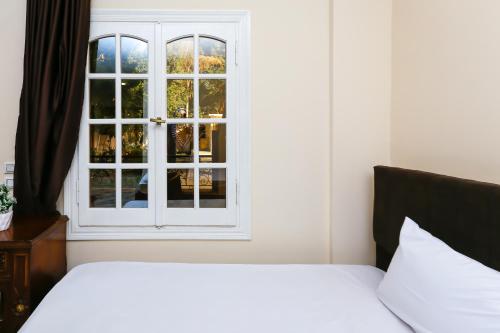 a bedroom with a white bed and a window at Turquoise Pyramids palace in Giza
