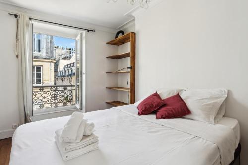 Cette chambre comprend un lit blanc avec des oreillers rouges et une fenêtre. dans l'établissement BnBNova - 2BR - Le Marais & Les Halles, à Paris