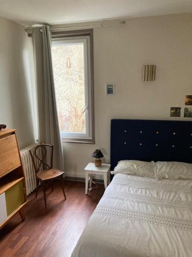 - une chambre avec un lit doté d'une tête de lit bleue et d'une fenêtre dans l'établissement Un havre de paix, à Fécamp