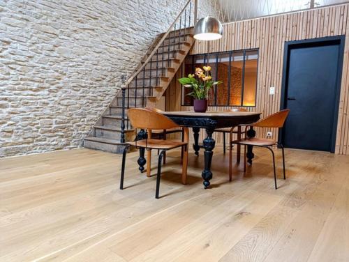 a dining room with a table and chairs and a staircase at Au Petit Bercail - Le Loft - Gite pour 4 personnes in Chiny