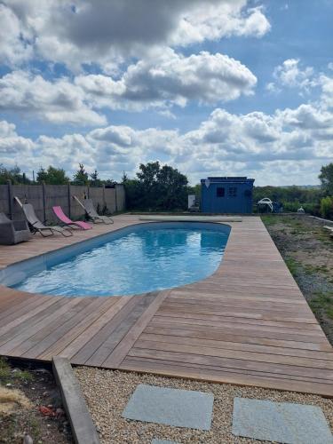 a swimming pool on a wooden deck with chairs around it at Petite maison bretonne 2 personnes accès piscine in Erquy