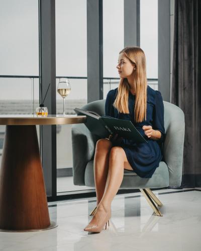 a woman sitting in a chair holding a book at Port Marine Hotel By HOLLYWOOD in Baku