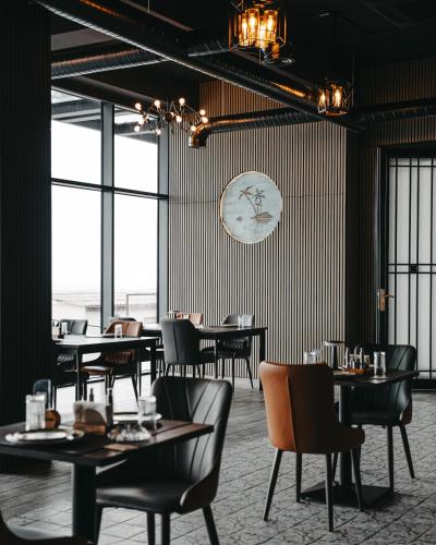 a restaurant with tables and chairs and a clock on the wall at Port Marine Hotel By HOLLYWOOD in Baku