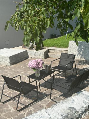 two chairs and a table with flowers on a patio at Il Giardino Segreto in Faggeto Lario 