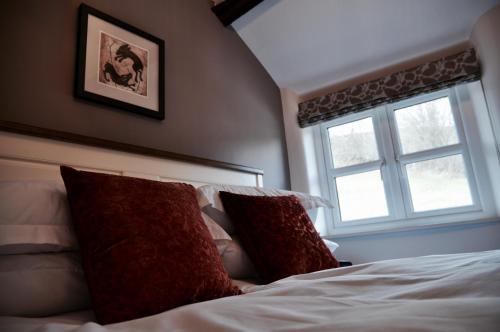 a bedroom with a bed with two pillows and a window at Pyne Arms in Barnstaple
