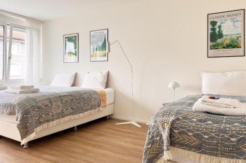 a white bedroom with two beds and a window at UP&GREAT Apartments - Chic Urban Homes in Zürich