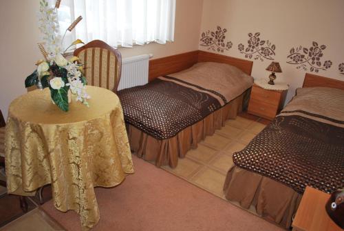 a room with two beds and a table with flowers on it at Ośrodek Wypoczynkowy Sowa in Lipniak