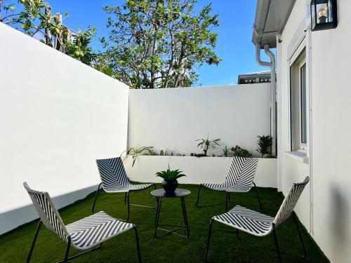a patio with chairs and a table and a white wall at Villa Tropéa in Les Cocos