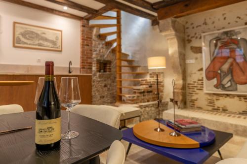 - une bouteille de vin assise sur une table avec un verre dans l'établissement L'Écrin sous le Château - Sauna et Raffinement - Classé 4 étoiles, à Blois