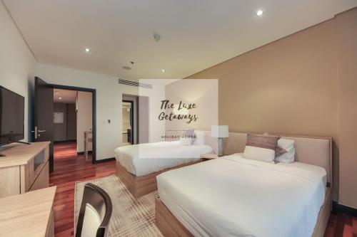 a hotel room with two beds and a television at Luxe Getaways Royal Amwaj Palm Jumeirah Resort Apartment Holiday Home in Dubai