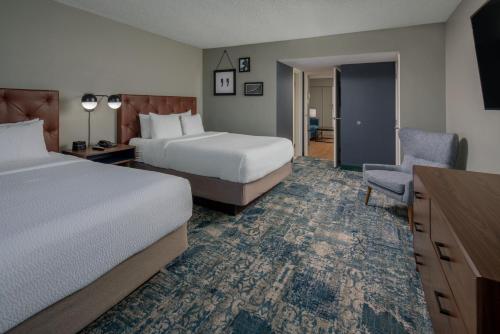 a hotel room with two beds and a chair at Four Points by Sheraton Suites Tampa Airport Westshore in Tampa