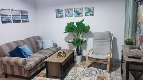 una sala de estar con un sofá y una silla en Apartamento Pacífico, en Chipiona