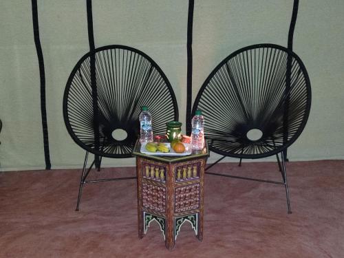 two chairs with a table with fruit on it at Erg Chebbi Star Camp in Merzouga