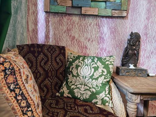 a couch with a pillow and a statue next to a table at Lovina Loca in Lovina