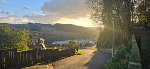 a view of a street with a fence and a hill at Corriefodly Holiday Park in Blairgowrie