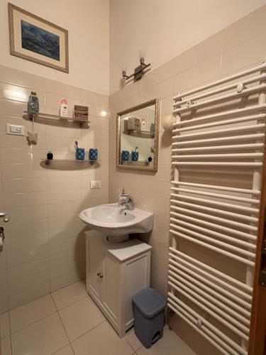a white bathroom with a sink and a mirror at La Casa del Glicine Tarzo in Fratta