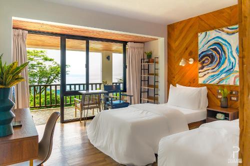 a hotel room with two beds and a balcony at Ponderosa Golf and Resort in Puerto Galera
