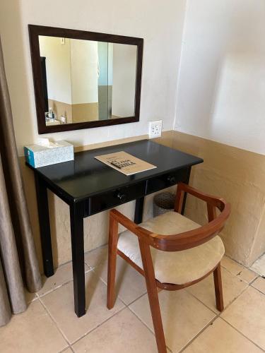 a black desk with a mirror and a chair at Ghanzi Farmhouse in Ghanzi