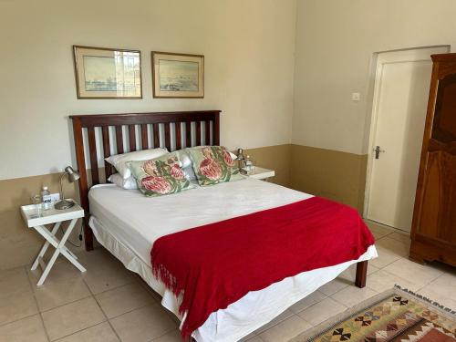 a bedroom with a large bed with a red blanket at Ghanzi Farmhouse in Ghanzi