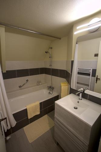 a bathroom with a tub and a sink and a mirror at Logis Hôtel Restaurant Manoir De L'Acherie in Sainte-Cécile