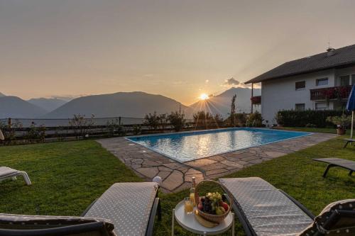 a swimming pool with a table and chairs in a yard at Panorama Hotel St Georgen in Schenna