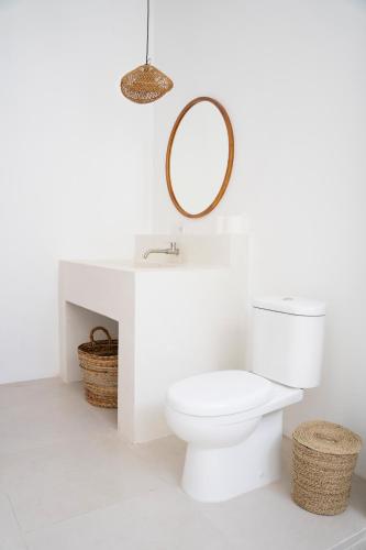 a white bathroom with a toilet and a mirror at Casa Yemi in Munggu