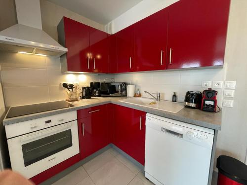 a kitchen with red cabinets and a white dishwasher at Modern and Bright home walk to beach with garage in Berck-sur-Mer