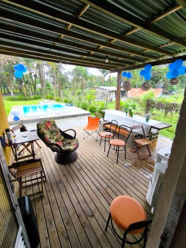 a deck with tables and chairs and a pool at Rancho Bertotti in Guaratuba