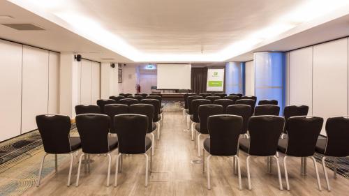 a conference room with black chairs and a white screen at Holiday Inn Newcastle-Jesmond by IHG in Newcastle upon Tyne