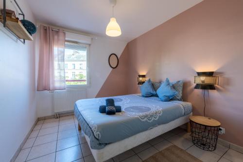 une chambre avec un lit avec des oreillers bleus dans l'établissement Chic appart avec parking au centre-ville, à Rouen