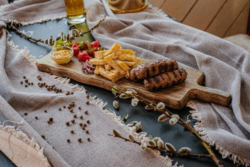 a wooden cutting board with meat and chips on a table at Ursa Mica Glamping Resort in Şirnea