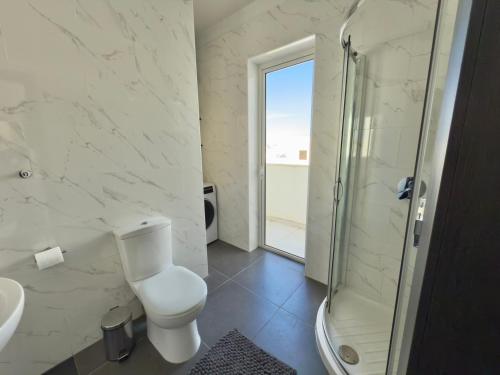 Un baño blanco con inodoro y ducha. en Modern penthouse, en Pieta