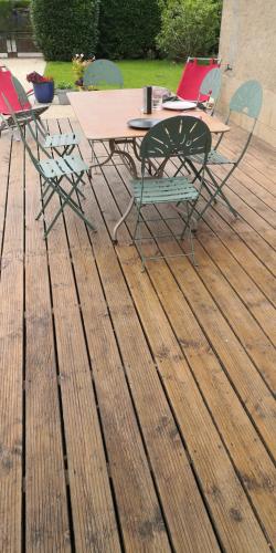une terrasse en bois avec une table et des chaises. dans l'établissement Gite La Mariette 10 couchages Brionnais Charolais, à Vauban