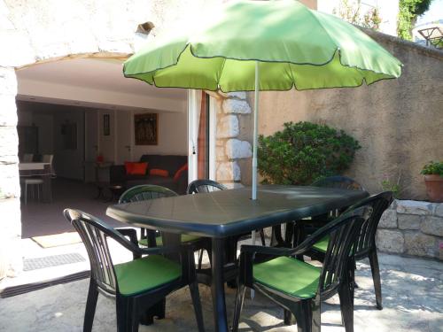 une table noire avec des chaises et un parasol vert dans l'établissement Appartement Castagniers, à Castagniers