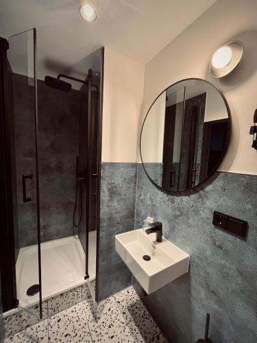 a bathroom with a sink and a shower and a mirror at Hostel SLEPS in Augsburg