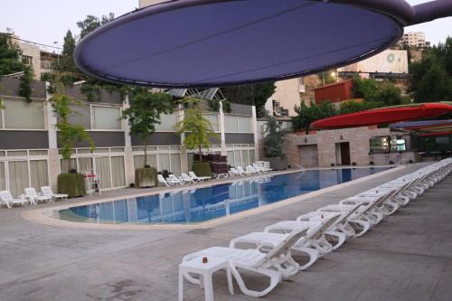 a pool with white lounge chairs and a large umbrella at Grand Kadri Hotel - History Marked by Cristal Lebanon in Zahlé