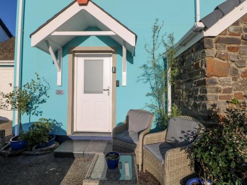 a blue house with two chairs and a door at The Hollybush in Kilgetty