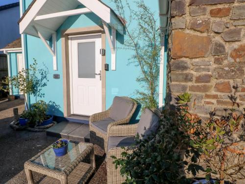a blue house with two chairs and a door at The Hollybush in Kilgetty